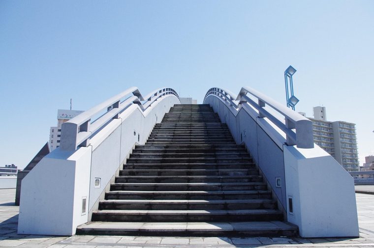 A wide white staircase rising towards a blue sky