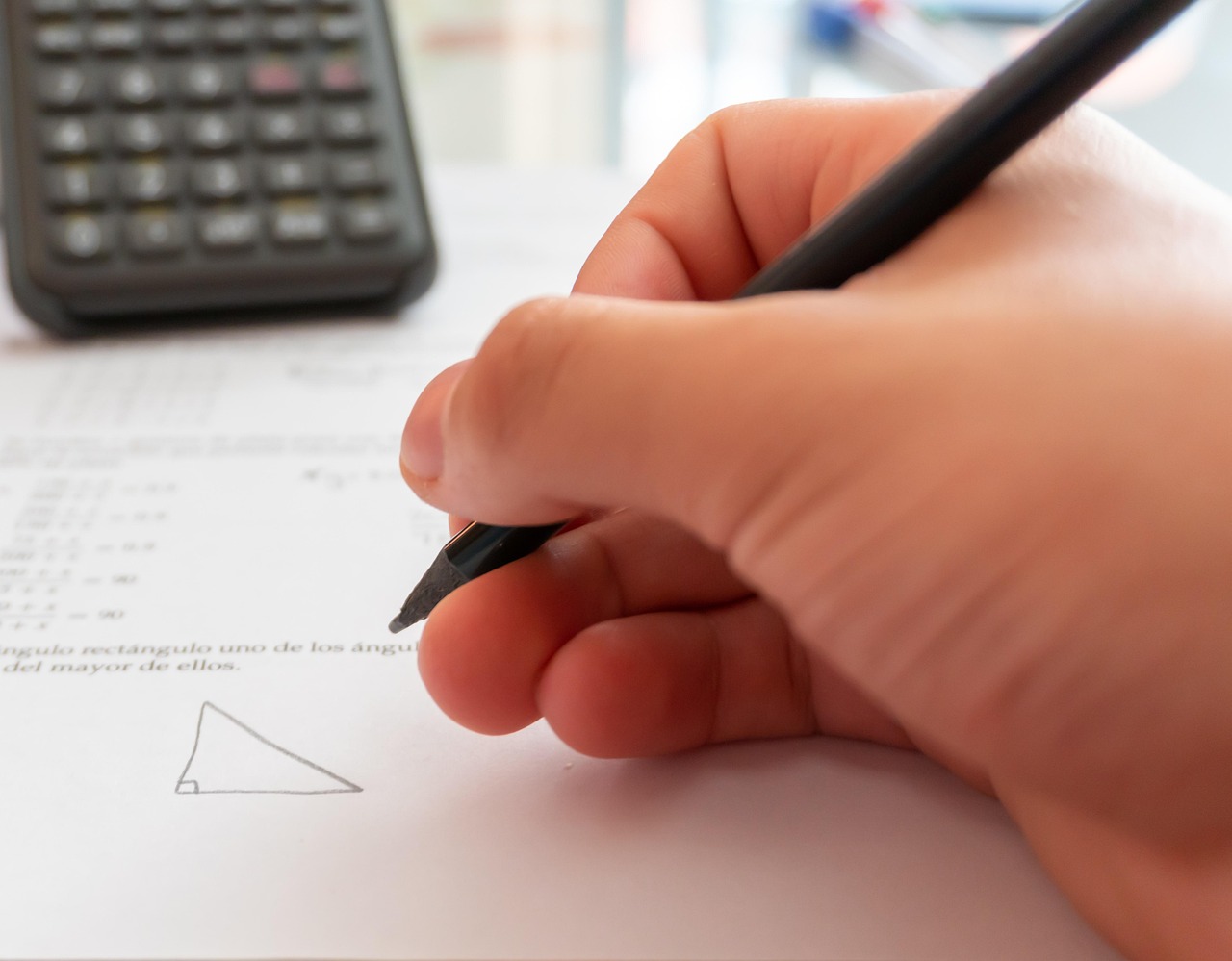 A hand writing beside a calculator