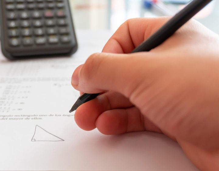 A hand writing beside a calculator