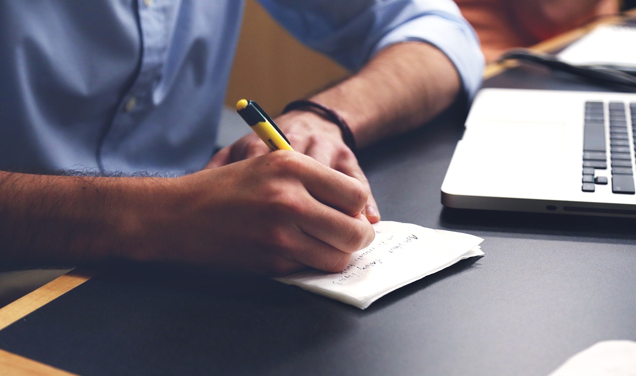 A person writing notes in a notebook at a desk